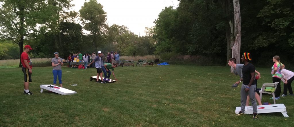 Students play corn hole at the university's nature preserve as part of the annual party hosted by the Matthewses to help build community.