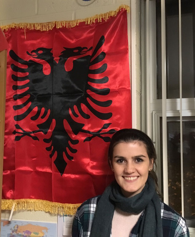 Junior Irena Xhari stands with the Albanian flag. Photo by Erika Byler
